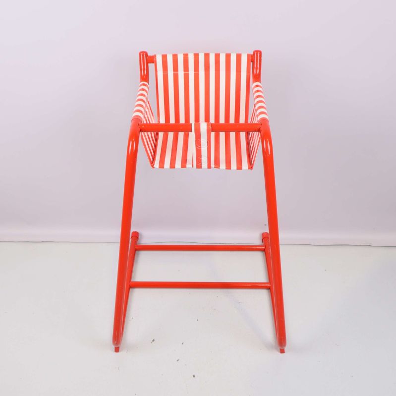 Barnstol i röd metall och rödvitt tyg sedd rakt framifrån