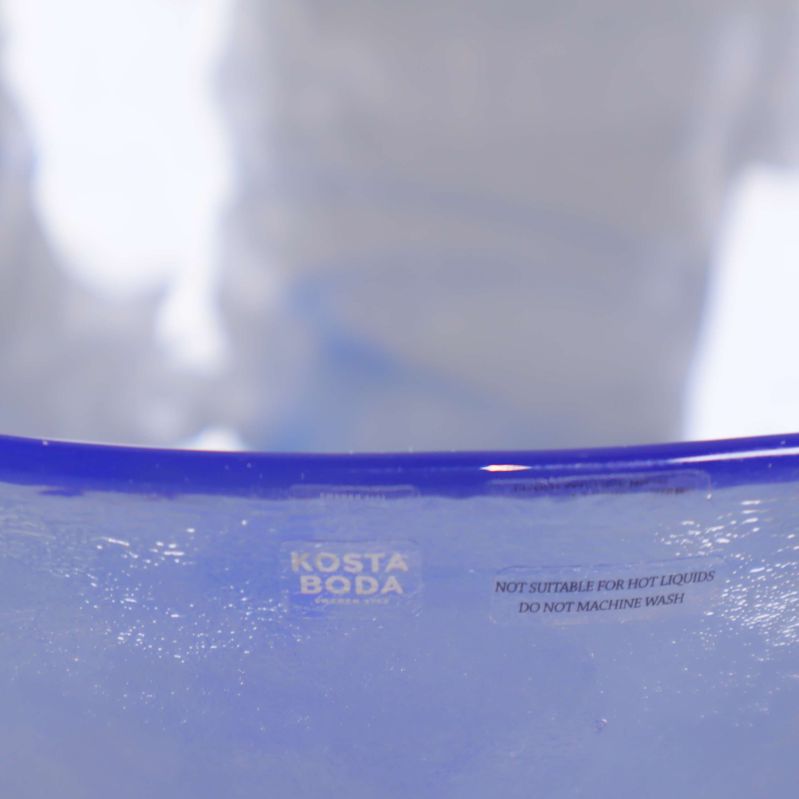 Närbild på Kosta Boda-logotyp och text på glasskålens kant
