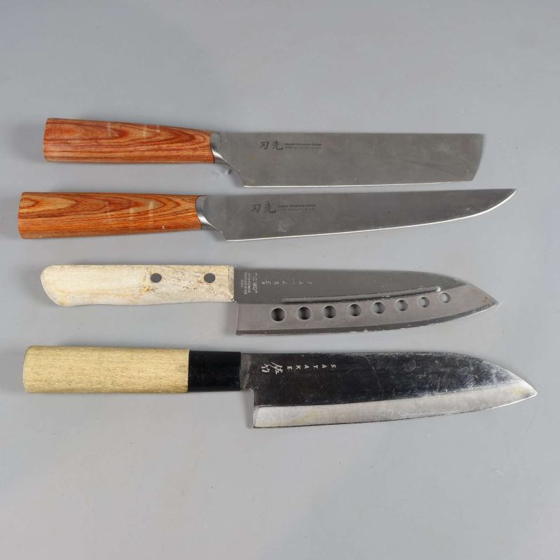 Fyra japanska köksknivar med olika träskaft upplagda på rad