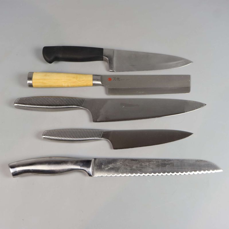 Fem köksknivar med olika handtag och blad i rad