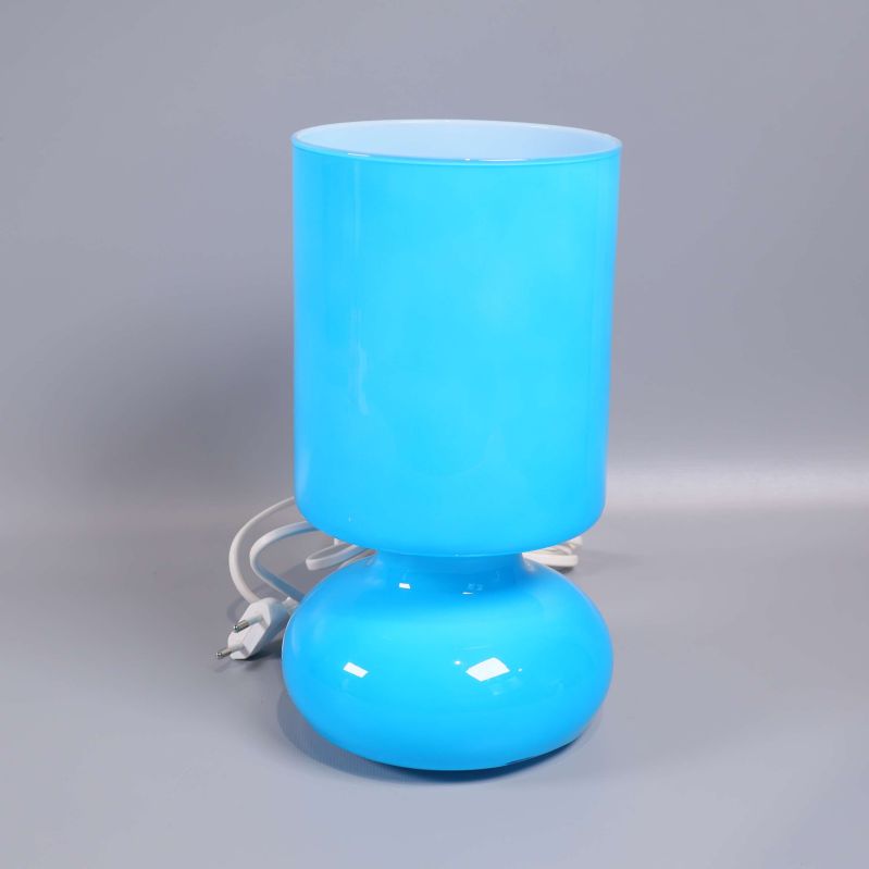 Blå cylinderformad bordslampa med vit sladd mot grå bakgrund