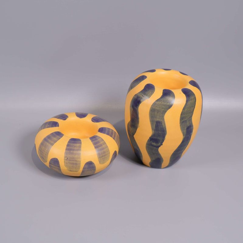 Två keramikljushållare med gula ochgrå inslag