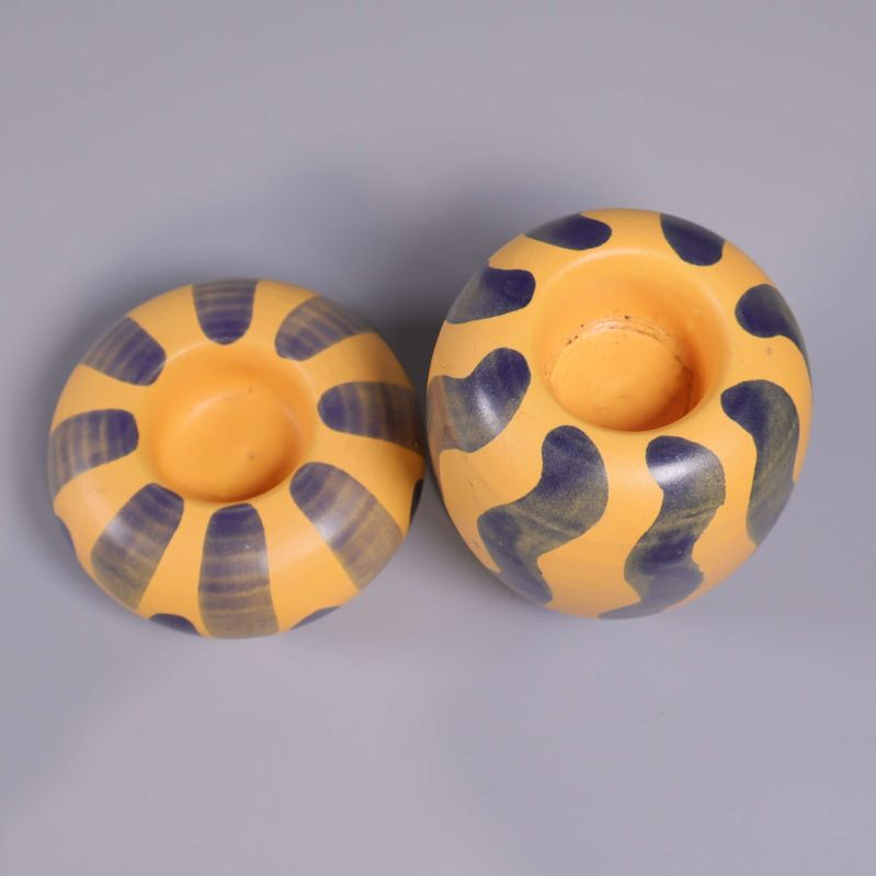 Tvåfärgade ljushållare sedda ovanifrån på grå bakgrund