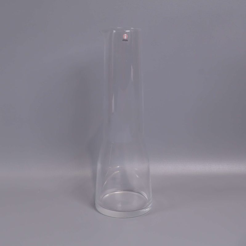 Hög smal karaff i klart glas mot grå bakgrund