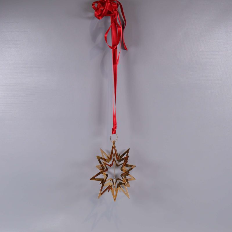 Julstjärna hänger i rött band mot väggen