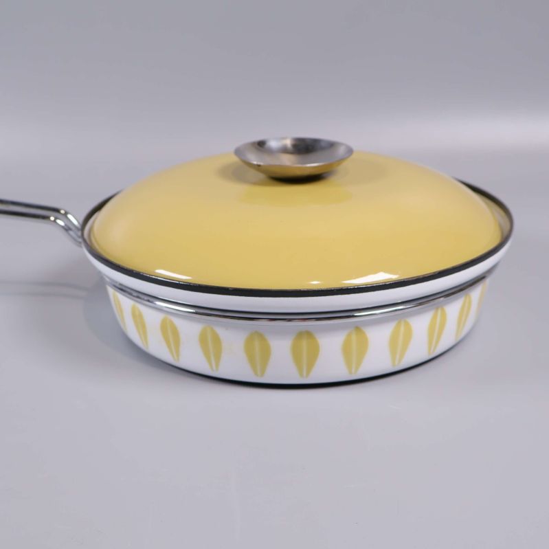 Närbild på stekpannans gula lock och mönstrad kant