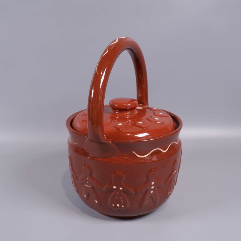 Keramikburk med lock och böjd hank sedd snett framifrån