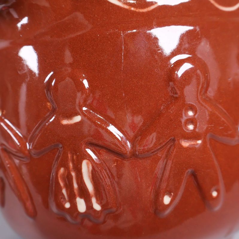 Närbild av reliefdekor med handhållande figurer på burken