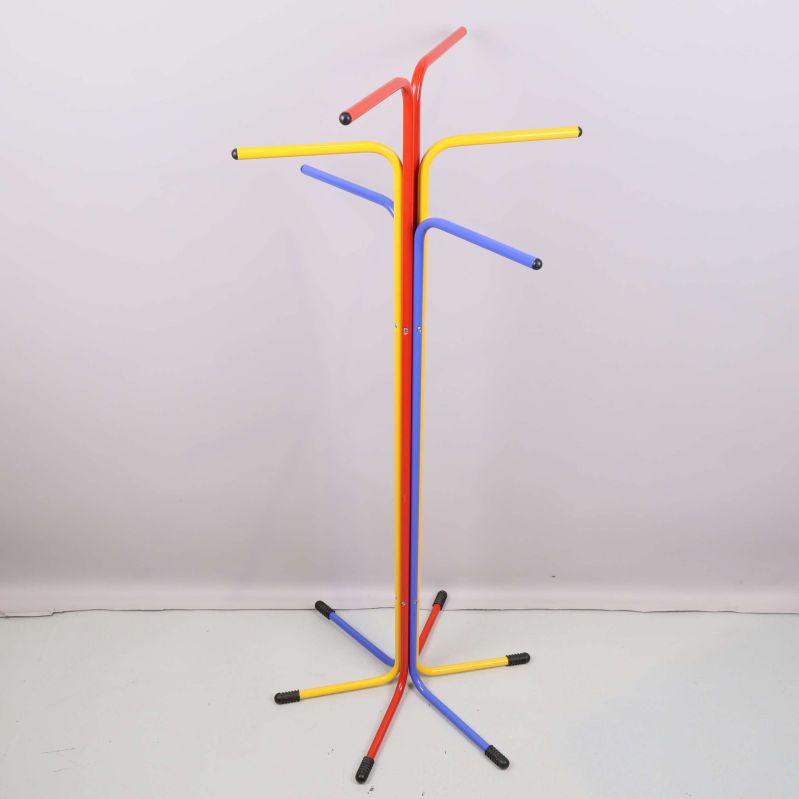Klädhängare med flera krokar i primärfärger stående mot vit vägg