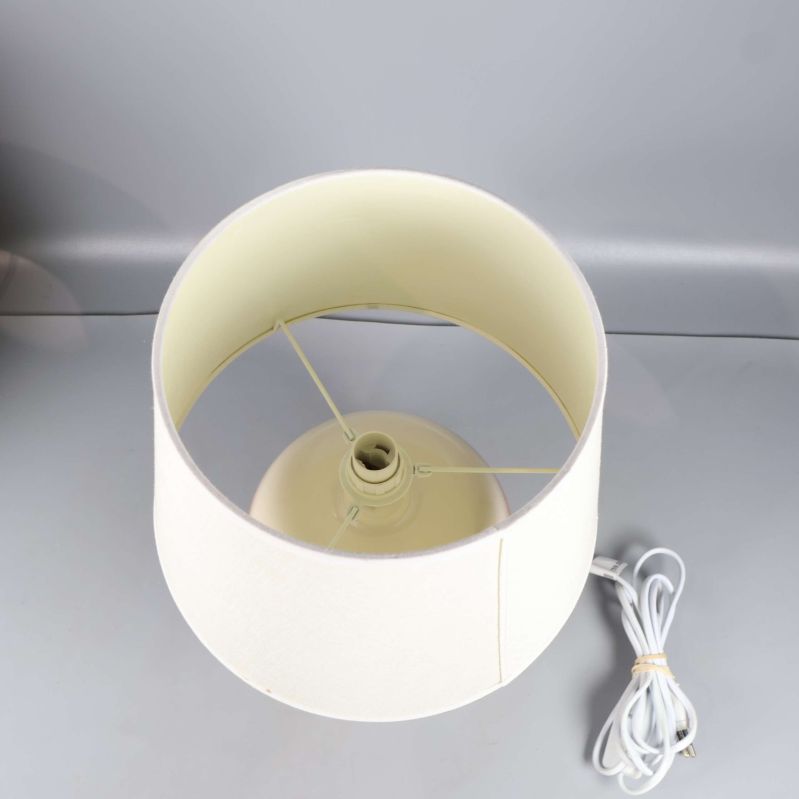 Vit lampskärm ovanifrån med gul fot synlig