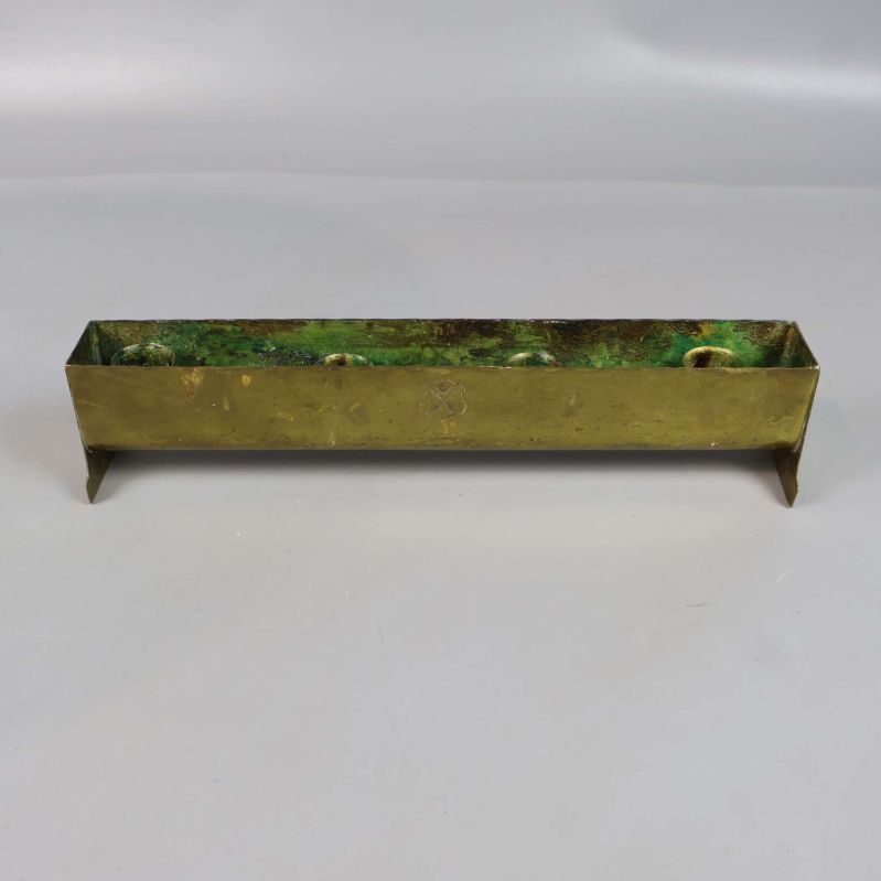 Avlång mässingsljusstake fotograferad rakt framifrån