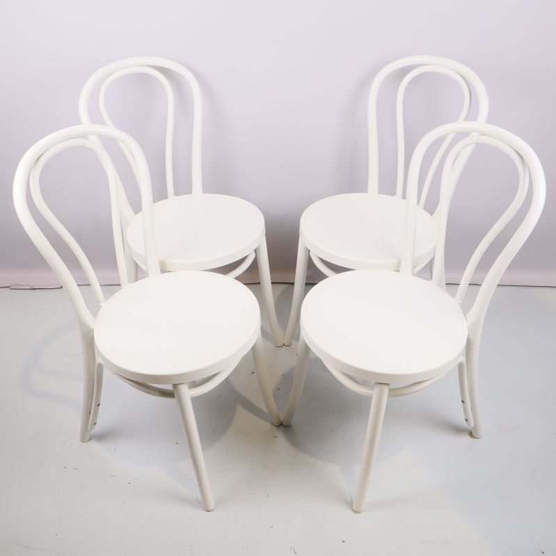 Fyra vita stolar uppställda mot ljus bakgrund