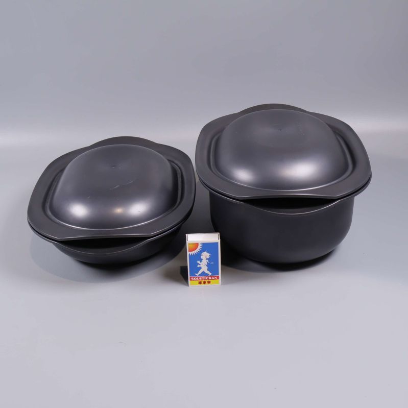 Två svarta gratängformar jämte tändsticksask för storleksjämförelse