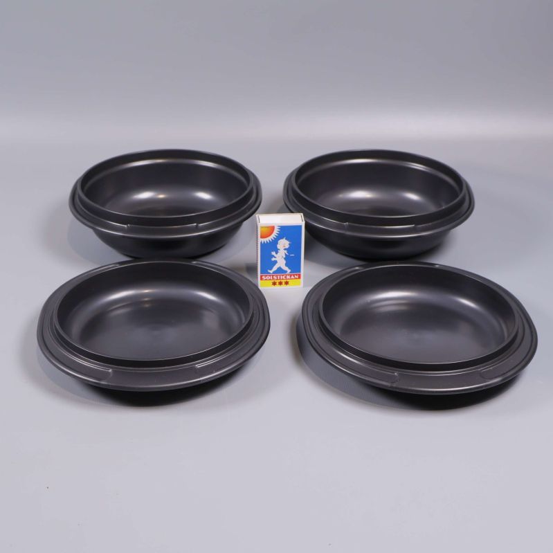 Fyra svarta skålar med tändsticksask som storleksjämförelse