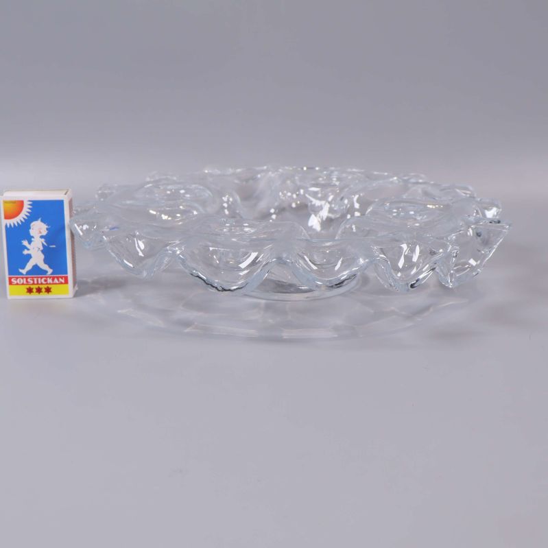 Sida av rund ljusstake i klarglas bredvid tändsticksask