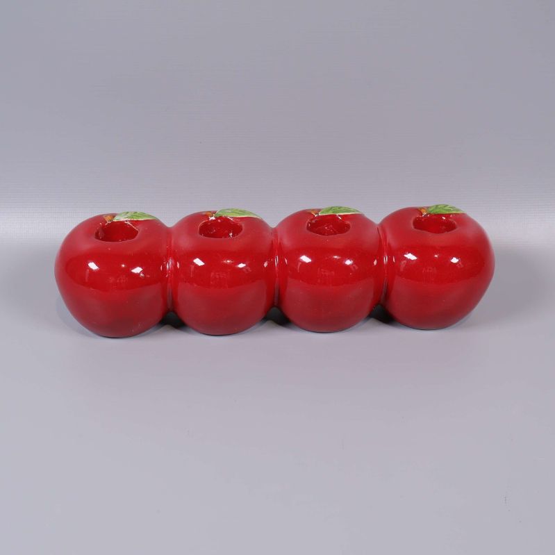 Fyra röda äppelformade ljushållare i rad