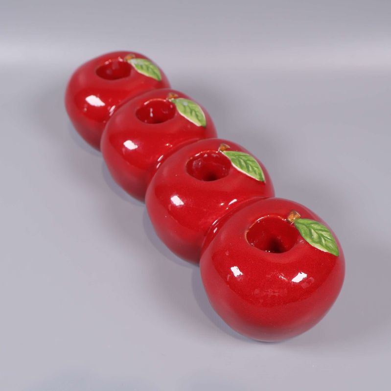 Fyra glänsande röda äpplen med gröna blad ovanpå