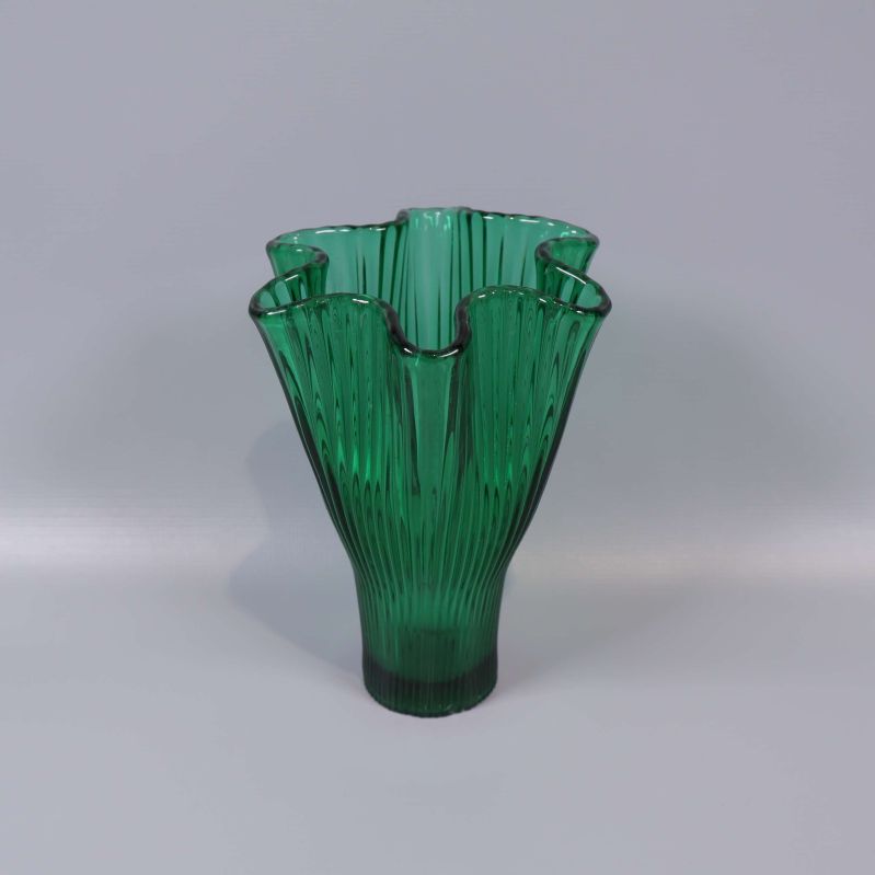 Grön veckad vas i glas mot ljus bakgrund