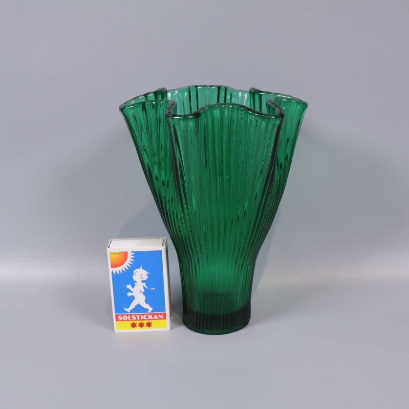 Grön vas i glas bredvid tändsticksask för storleksjämförelse