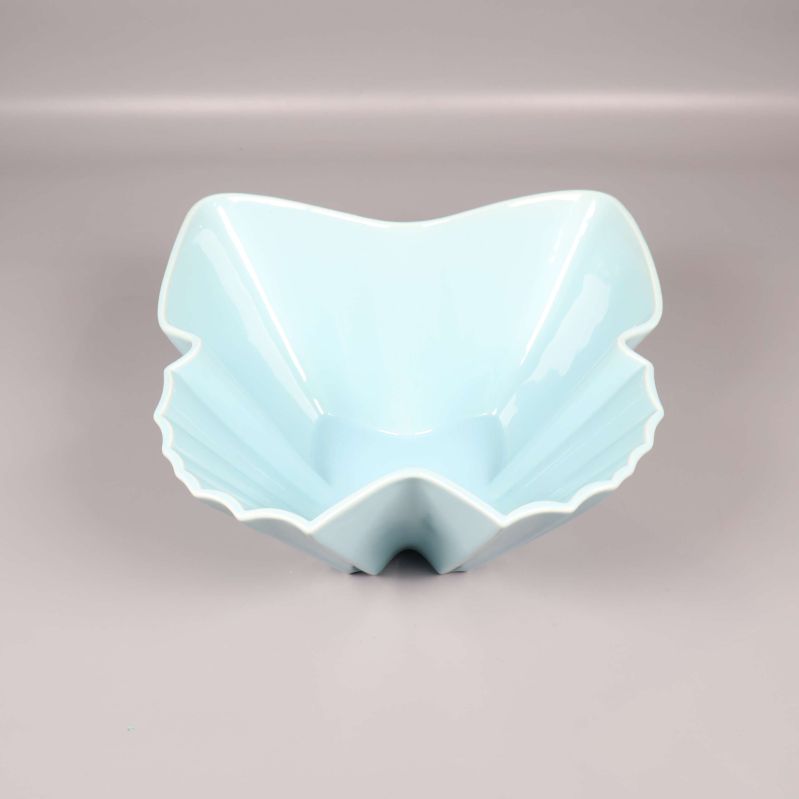 Ljusblå vågig skål sedd framifrån mot grå bakgrund