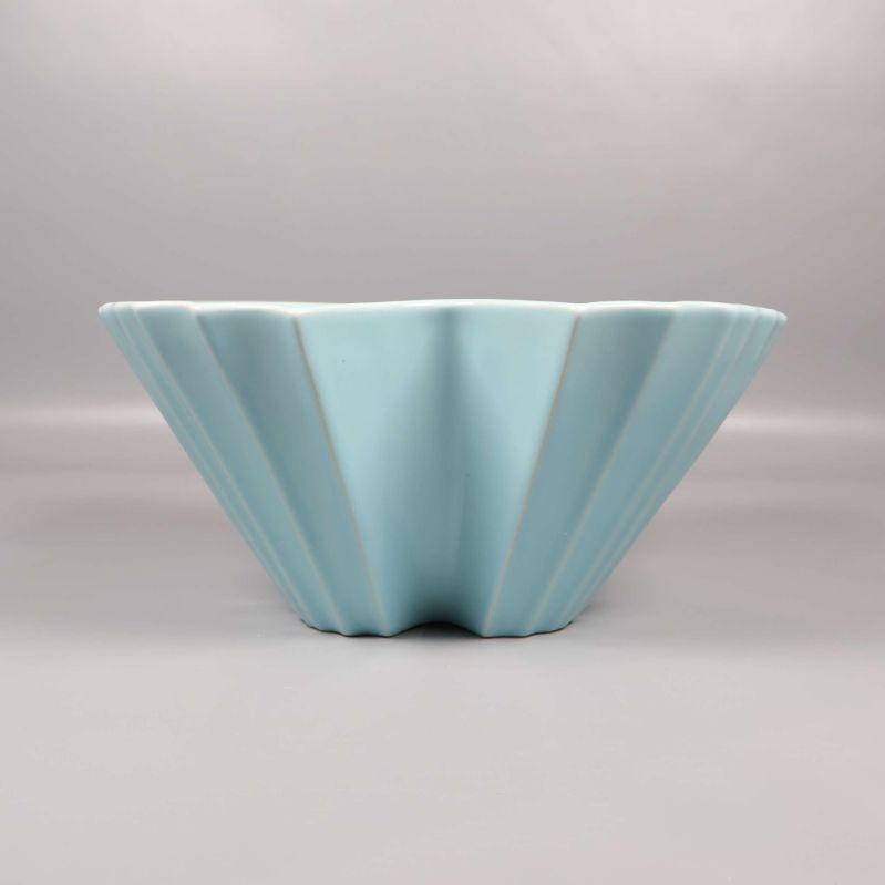 Ljusblå skål sedd från sidan visar veckad form