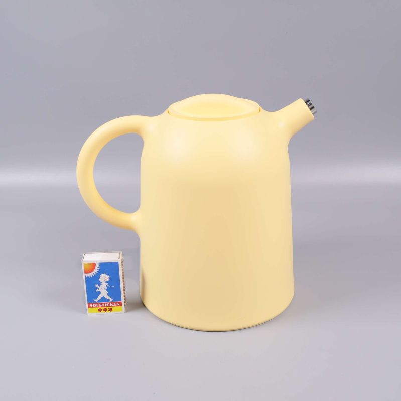 Gul termoskanna bredvid tändsticksask i studio