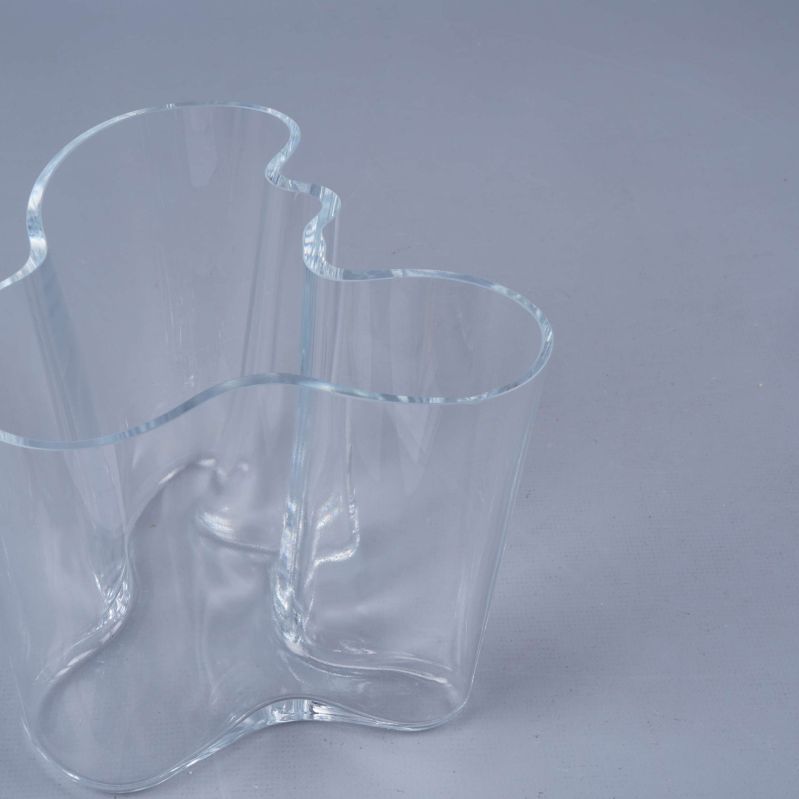 Klar glasvas med vågig kant på ljus yta