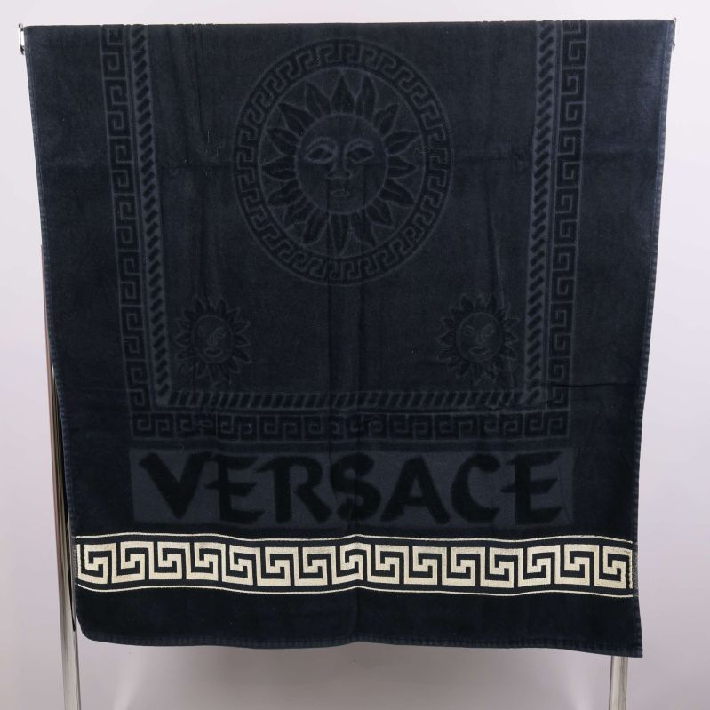 Utbredd svart handduk med Versace-logga och guldmönster