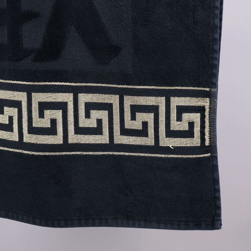 Närbild på hörn av handduk med guldig bård