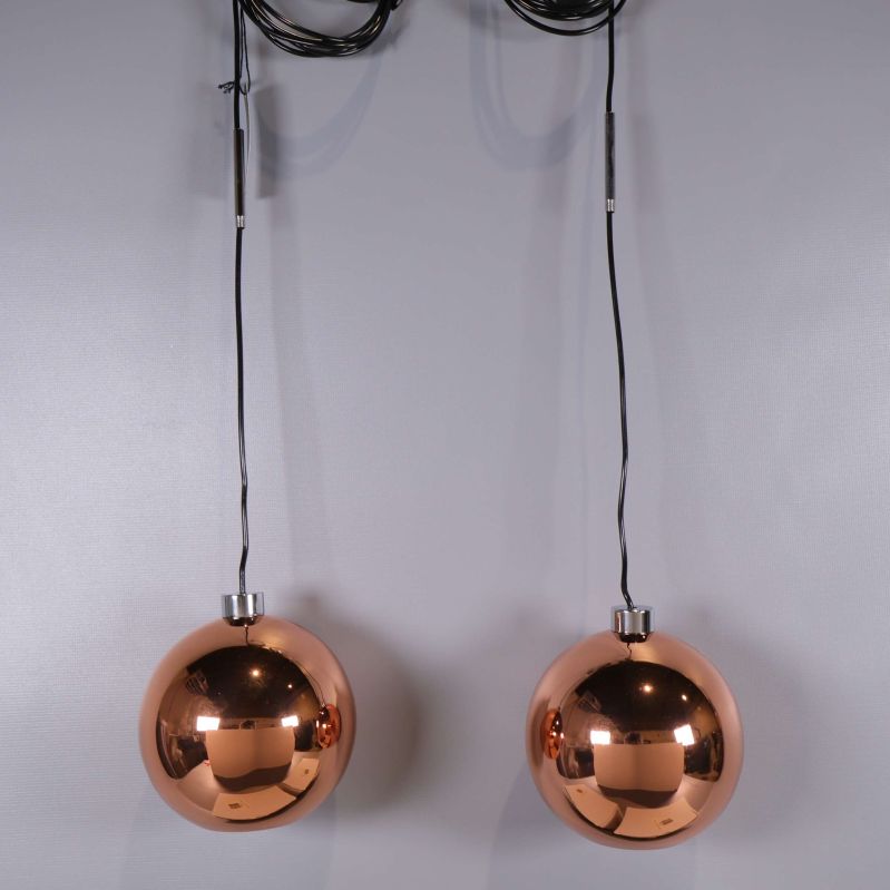 Takpendlar i koppar färg hängande mot grå bakgrund