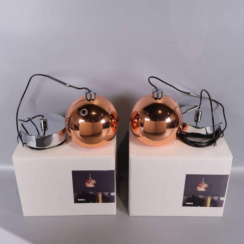 Två kopparfärgade klotformade pendellampor på kartonger
