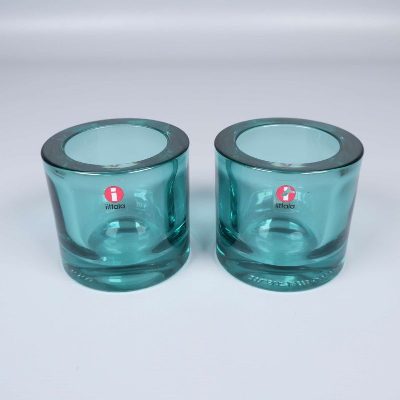 Två turkosa glasljuslyktor med Iittala-logga på vit bakgrund