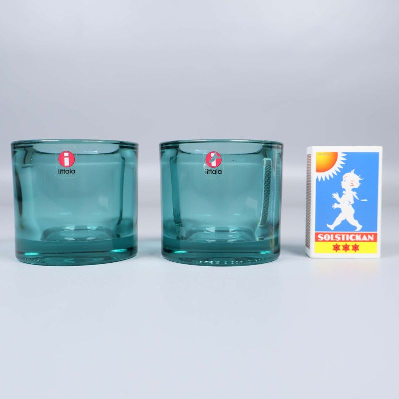 Två ljuslyktor i turkost glas bredvid tändsticksask