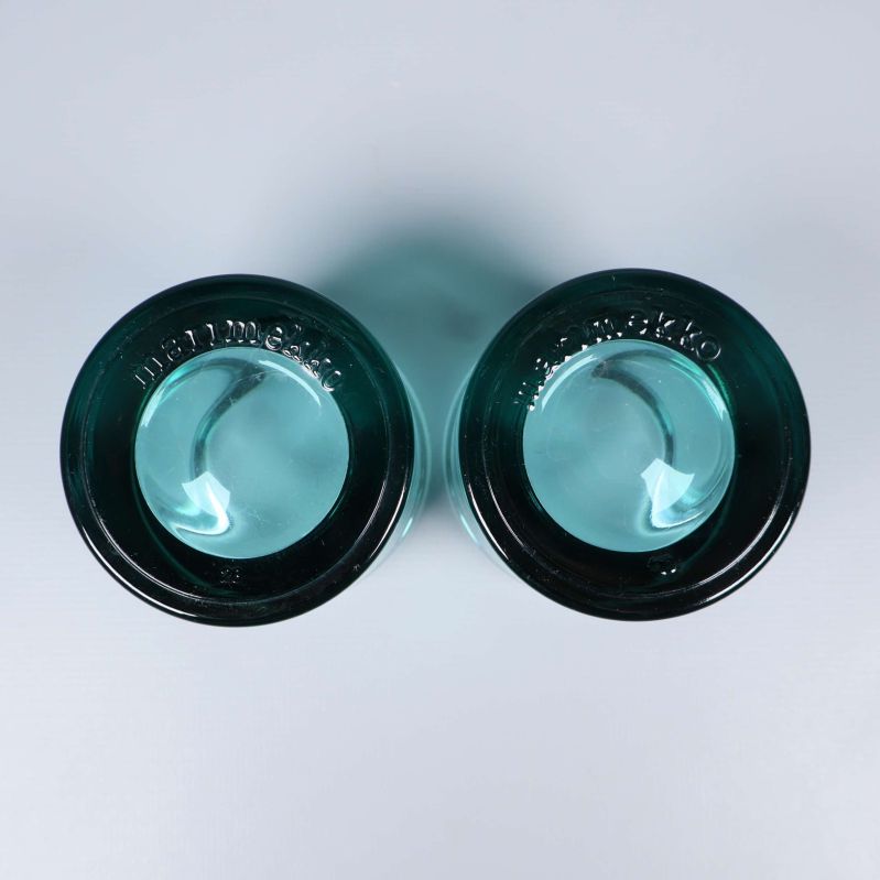 Undersida av två turkosa ljuslyktor med gravyr