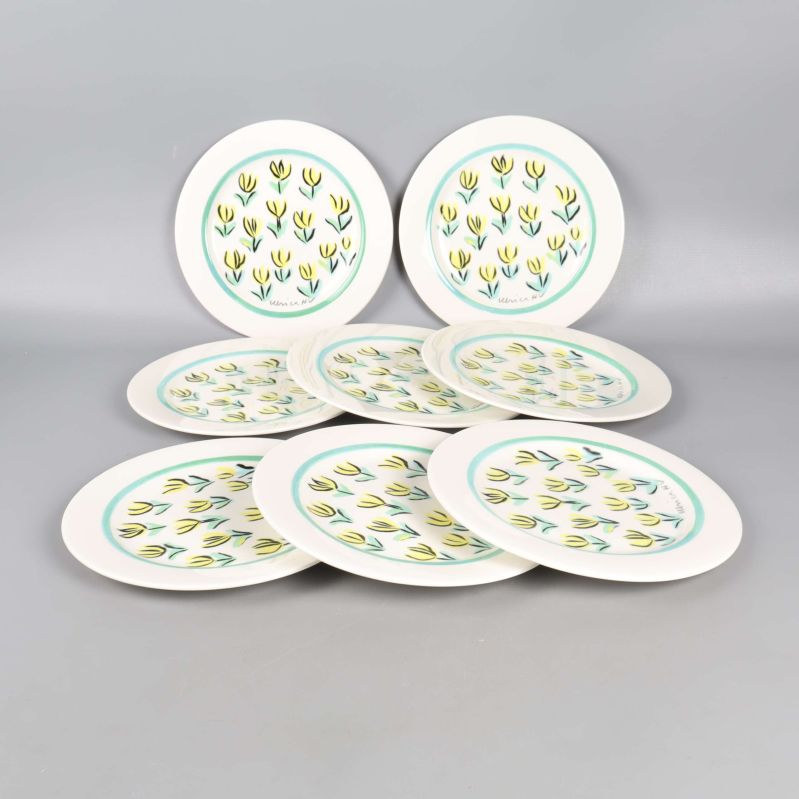 Åtta assietter med färgglada blommor uppställda