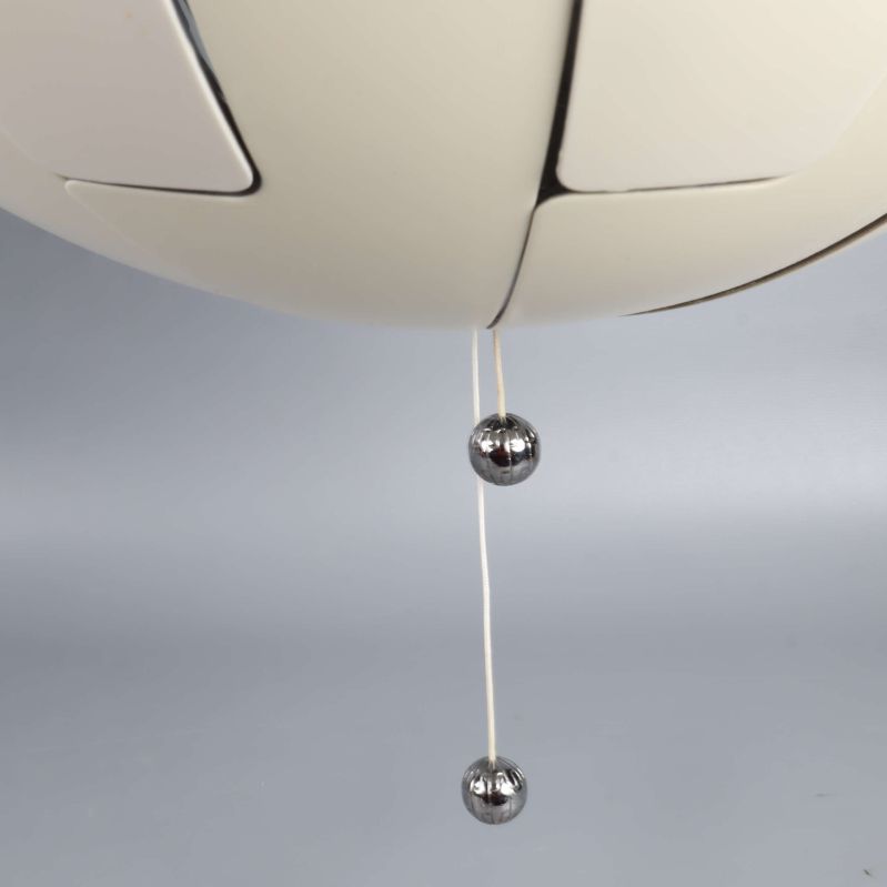 Närbild på två metallkulor i änden av lampans dragsnöre