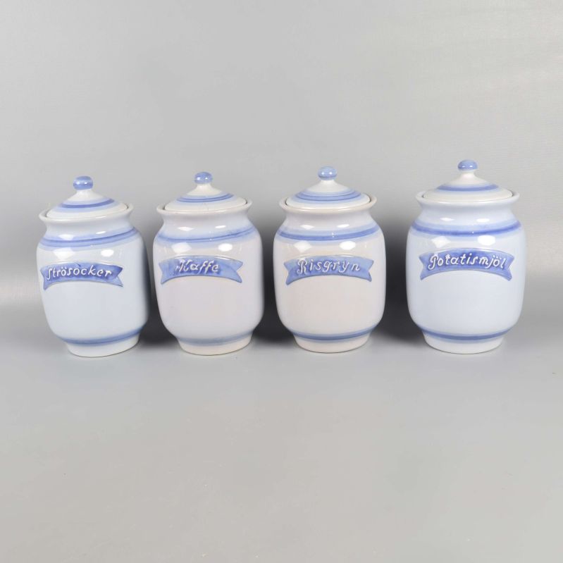 Fyra keramikburkar med blå text och dekorativa lock