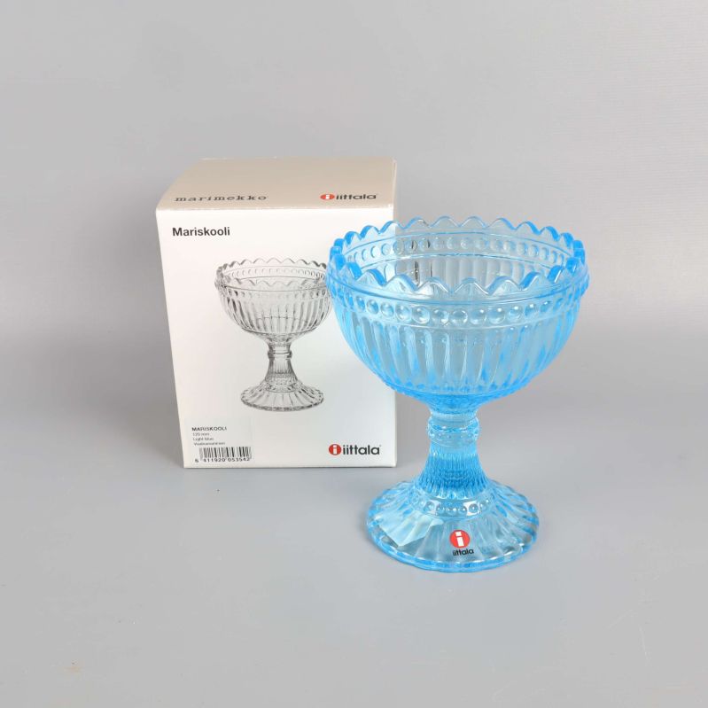 Ljusblå glasskål på fot bredvid sin kartongförpackning