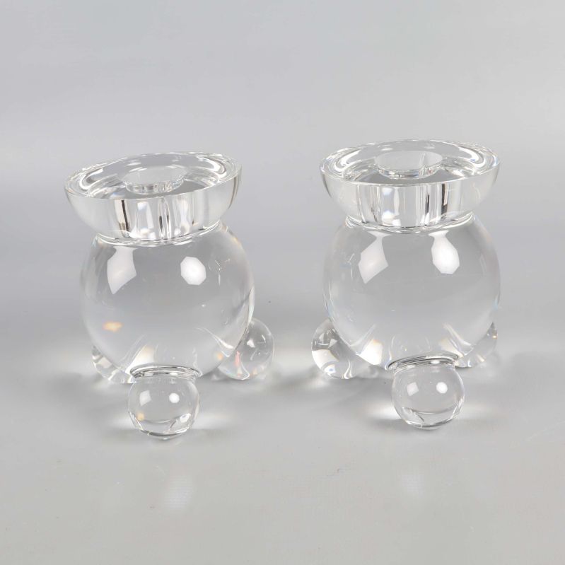Närbild på två klara runda glasljusstakar med tre ben