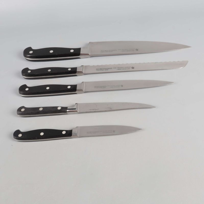 Fem köksknivar placerade på rad med bladen mot vänster