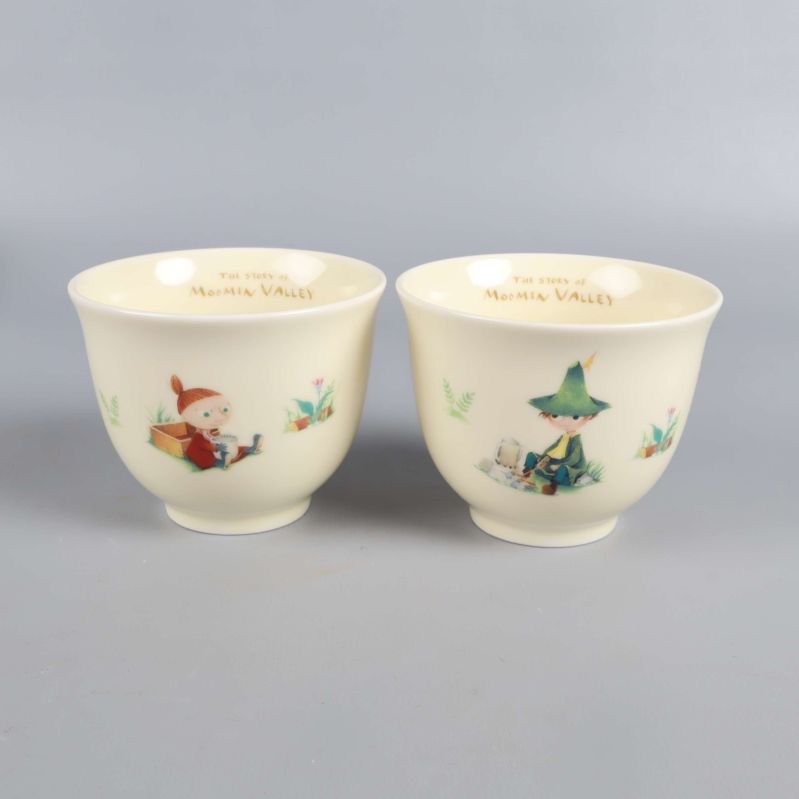 Två koppar med Mumintrollet-karaktärer och detaljerade illustrationer