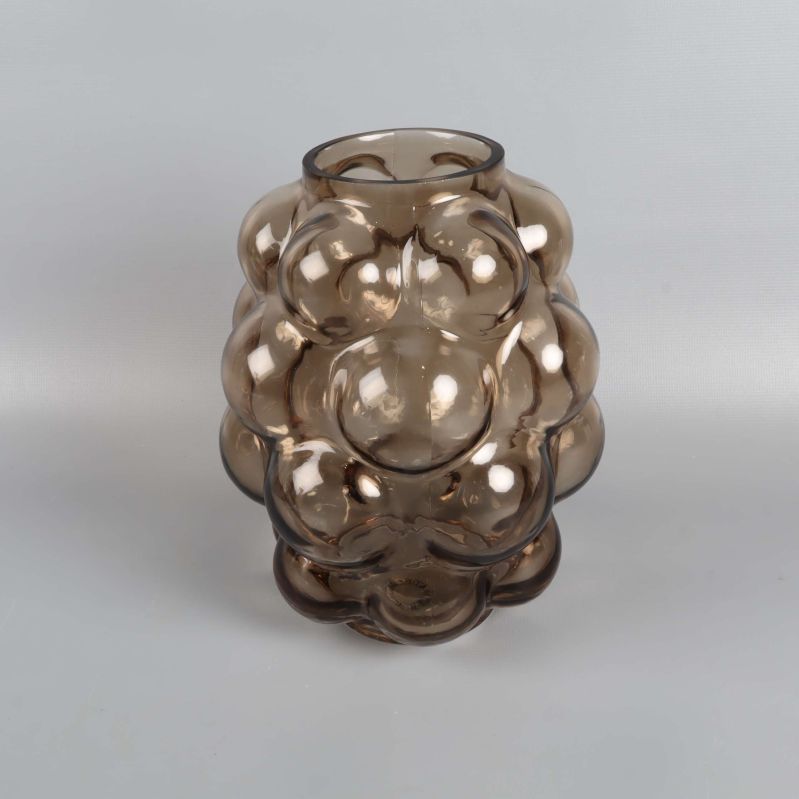 Vas i rökfärgat glas med bubblig struktur mot ljus bakgrund