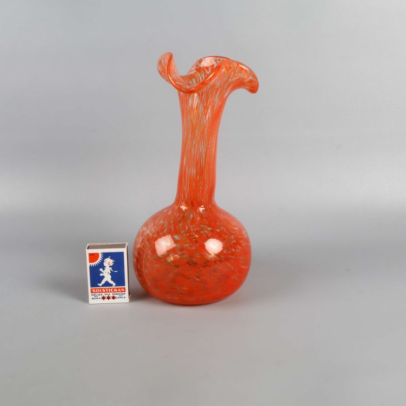 Handblåst orange vas bredvid tändsticksask för storleksjämförelse