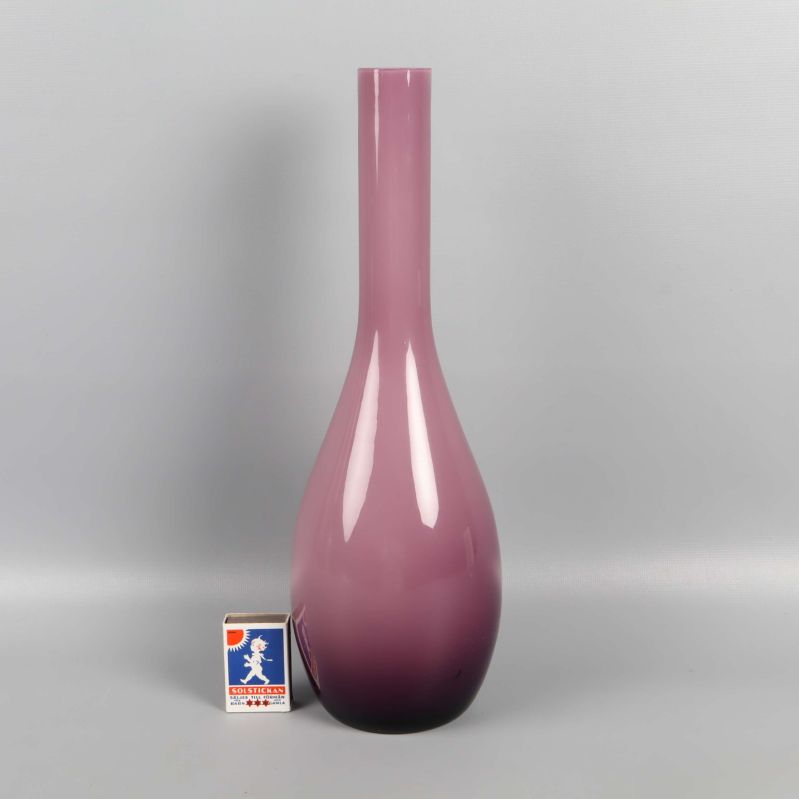 Lilarosa vas bredvid tändsticksask för storleksreferens