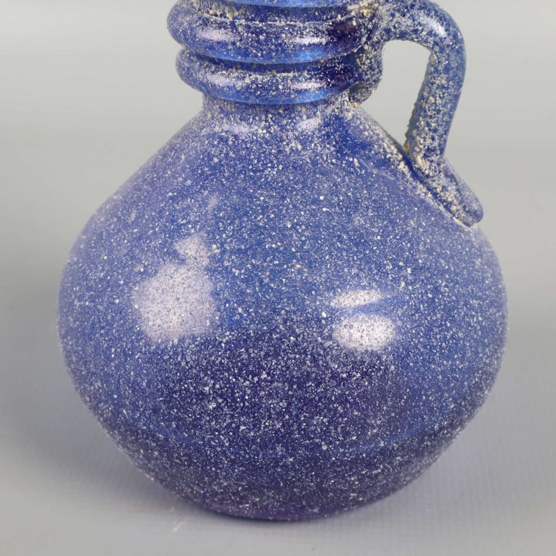 Närbild på blå glasvasens mage och handtag