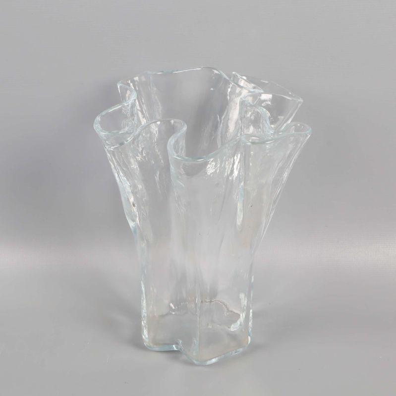 Transparent vågig vas placerad mot neutral bakgrund