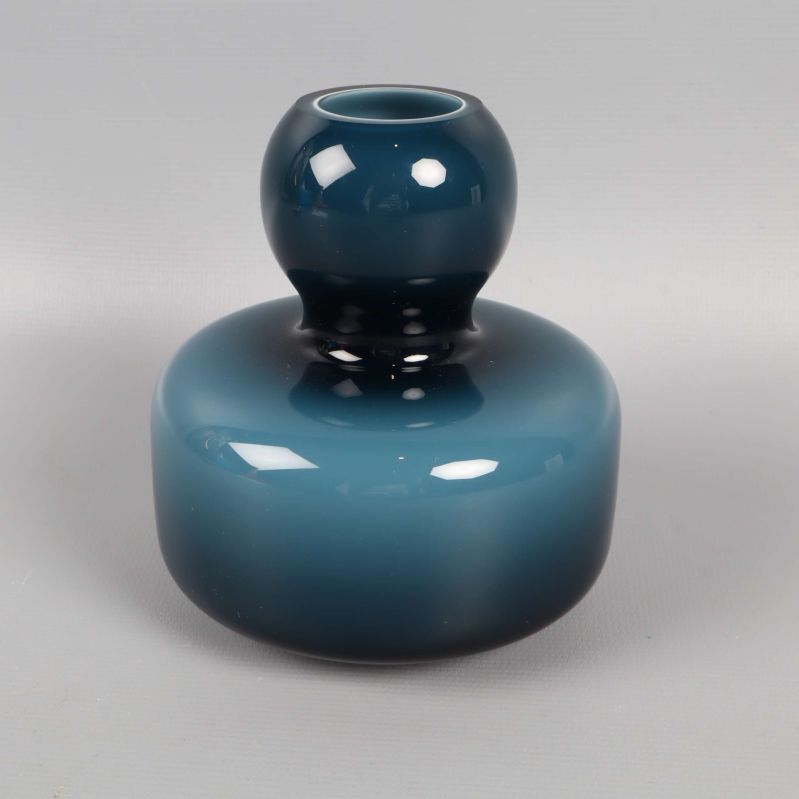 Rund designad blå glasvas mot ljus bakgrund