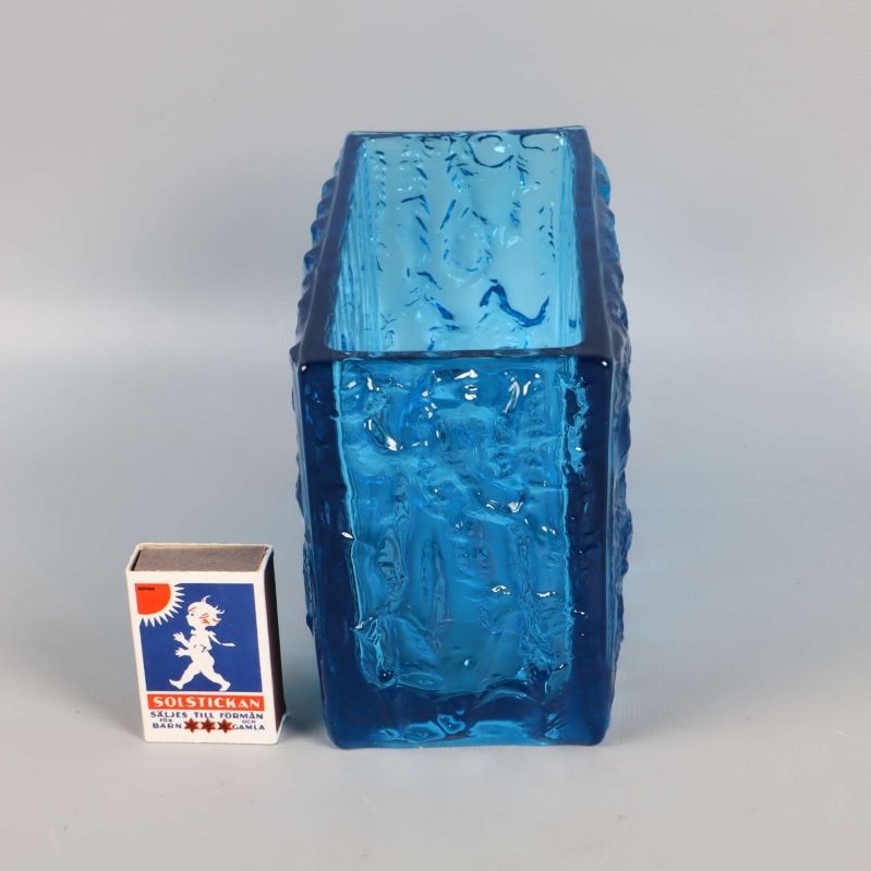 Vas i blått glas stående bredvid tändsticksask för storleksjämförelse