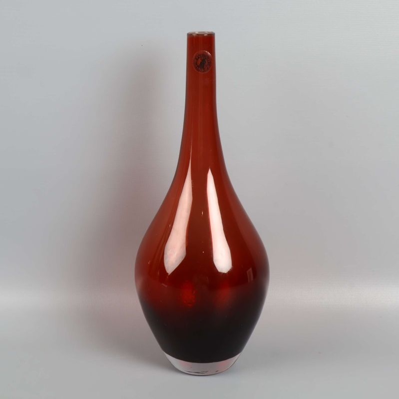 Hög vas i rödbrunt glas mot ljus bakgrund