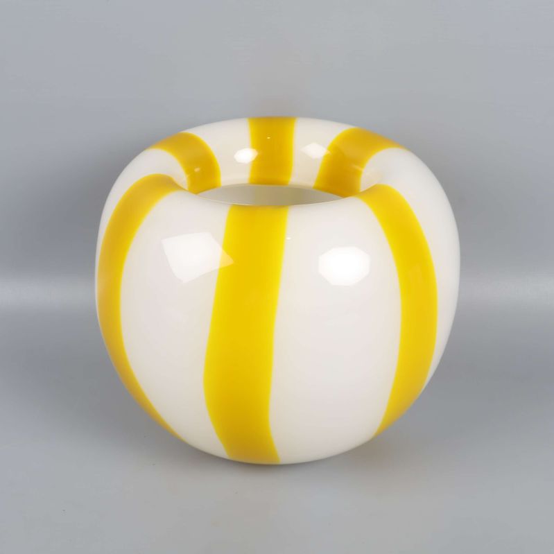Rund vas med gula och vita ränder mot grå bakgrund
